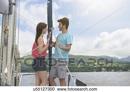 Young couple standing on bow of yacht sailing on lake under bright sunlight View Large Photo Image Stock Image - Young couple standing on bow of yacht sailing on lake under bright sunlight. Fotosearch
