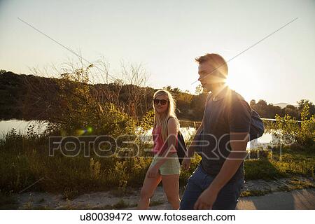 Young couple strolling along riverside at sunset View Large Photo Image Stock Image - Young couple strolling along riverside at sunset. Fotosearch