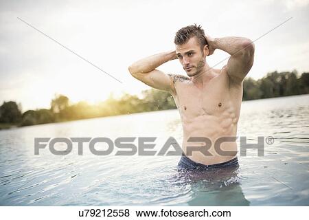 Young handsome man standing with hands behind his head in lake View Large Photo Image Stock Photo - Young handsome man standing with hands behind his head in lake. Fotosearch