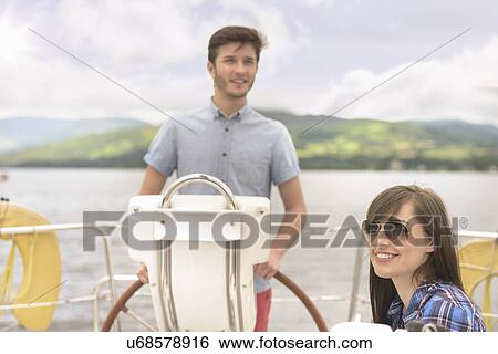 Young man at the helm of yacht with girlfriend in sunglasses View Large Photo Image Stock Photograph - Young man at the helm of yacht with girlfriend in sunglasses. Fotosearch