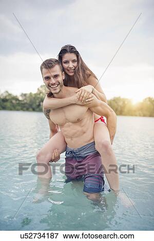 Young man carrying his girlfriend on piggyback in lake View Large Photo Image Stock Photo - Young man carrying his girlfriend on piggyback in lake. Fotosearch