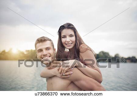 Young man giving his girlfriend a piggyback in lake View Large Photo Image Stock Image - Young man giving his girlfriend a piggyback in lake. Fotosearch