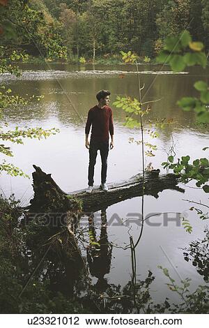 Young man looking from tree trunk in river View Large Photo Image Stock Image - Young man looking from tree trunk in river. Fotosearch