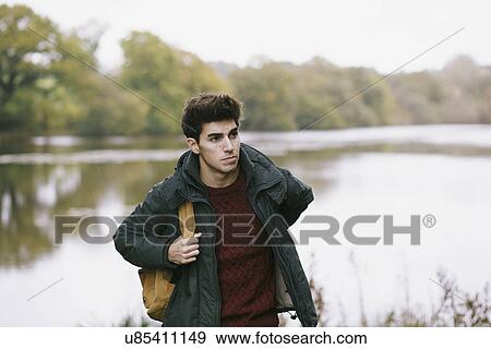 Young man strolling along riverbank View Large Photo Image Stock Photo - Young man strolling along riverbank. Fotosearch