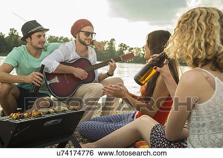 Stock Photograph - Young man with friends playing guitar. Fotosearch