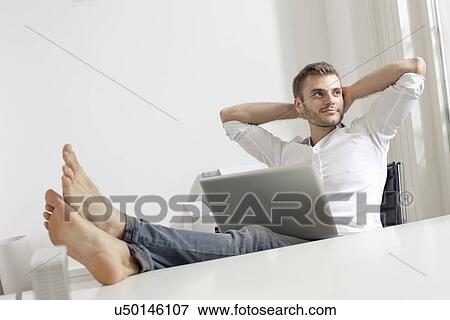 Stock Photo - Young man with laptop relaxing. Fotosearch