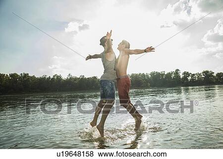 Young men chest bumping in lake View Large Photo Image Stock Photo - Young men chest bumping in lake. Fotosearch