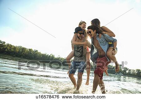 Young men giving young women piggy backs View Large Photo Image Stock Photograph - Young men giving young women piggy backs. Fotosearch
