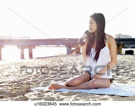 Stock Photography - Young woman drinking coffee on beach, Port Melbourne, Melbourne, Victoria, Australia. Fotosearch