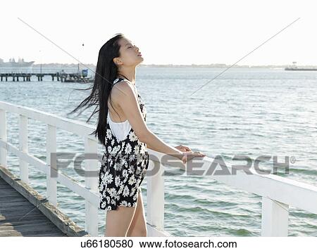 Stock Image - Young woman gazing from pier, Port Melbourne, Melbourne, Victoria, Australia. Fotosearch