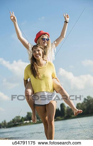 Young woman giving friend piggy back View Large Photo Image Stock Photography - Young woman giving friend piggy back. Fotosearch