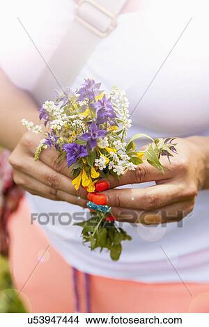 Young woman holding bunch of wild flowers View Large Photo Image Picture - Young woman holding bunch of wild flowers. Fotosearch