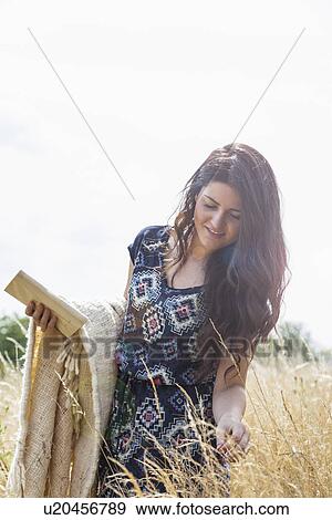 Young woman in field with blanket and book View Large Photo Image Stock Photo - Young woman in field with blanket and book. Fotosearch