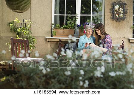 Picture - Young woman listening to music with grandmother. Fotosearch