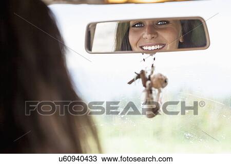 Stock Image - Young woman looking in rear view mirror. Fotosearch