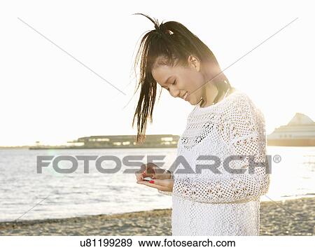 Young woman on beach looking down at sea shell, Port Melbourne, Melbourne, Victoria, Australia View Large Photo Image Stock Photo - Young woman on beach looking down at sea shell, Port Melbourne, Melbourne, Victoria, Australia. Fotosearch
