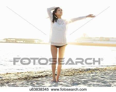 Stock Photography - Young woman on sunlit beach with arm out, Port Melbourne, Melbourne, Victoria, Australia. Fotosearch