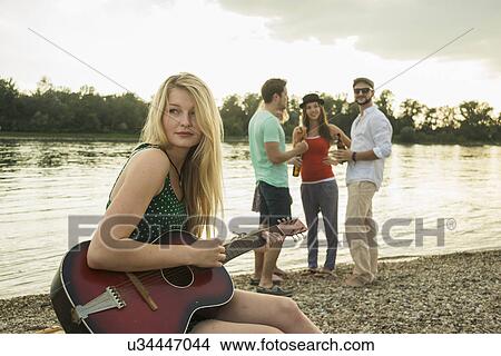 Young woman playing guitar by lake View Large Photo Image Picture - Young woman playing guitar by lake. Fotosearch