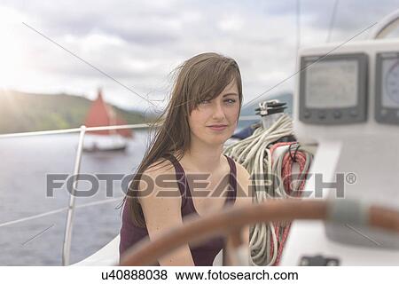 Stock Photo - Young woman relaxing on yacht, looking away. Fotosearch