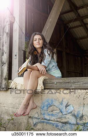 Stock Photography - Young woman sitting by barn, portrait. Fotosearch
