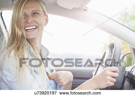 Young woman smiling behind wheel of car View Large Photo Image Stock Photo - Young woman smiling behind wheel of car. Fotosearch
