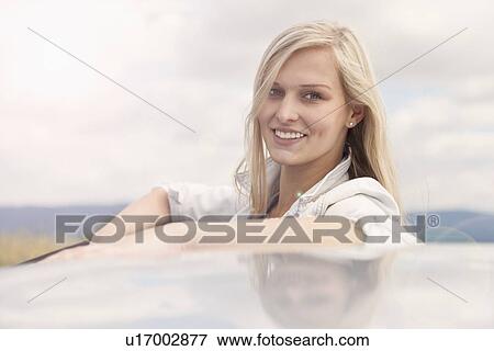 Young woman smiling beside car View Large Photo Image Stock Photo - Young woman smiling beside car. Fotosearch