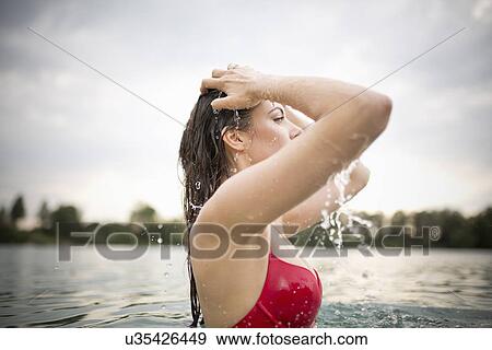 Young woman splashing water in hair in lake View Large Photo Image Stock Photo - Young woman splashing water in hair in lake. Fotosearch
