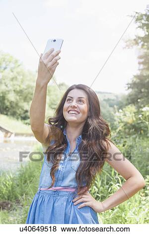 Stock Photo - Young woman taking selfie. Fotosearch