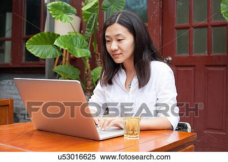 Stock Photography - Young woman using laptop, outdoors. Fotosearch