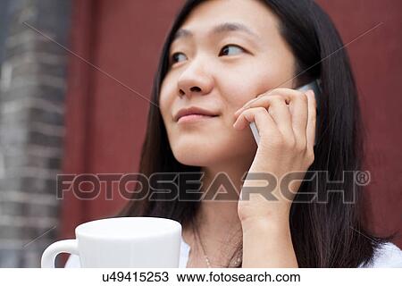 Stock Image - Young woman using mobile phone. Fotosearch