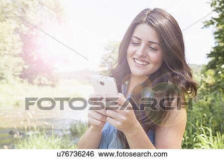 Stock Photograph - Young woman using smartphone. Fotosearch