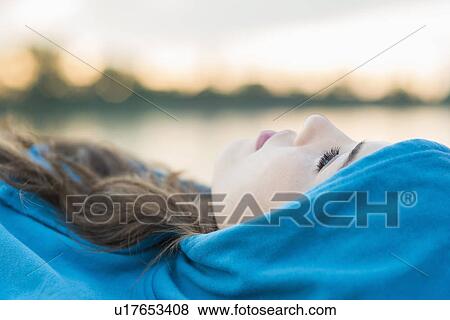 Stock Photo - Young woman wearing blue hooded top lying down. Fotosearch