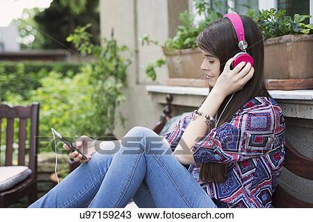 Young woman wearing headphones, listening to music View Large Photo Image Stock Image - Young woman wearing headphones, listening to music. Fotosearch