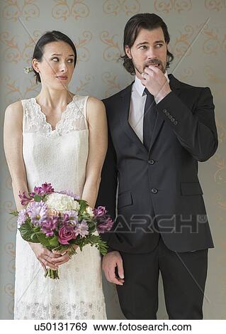 Anxious bride and groom posing with bunch of flowers View Large Photo Image Stock Photo - Anxious bride and groom posing with bunch of flowers. Fotosearch