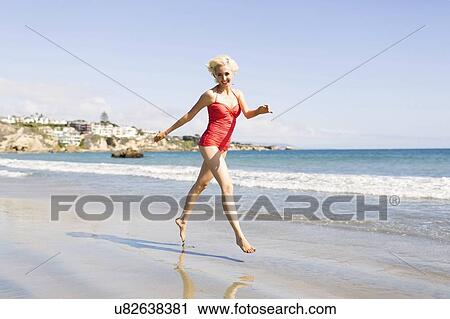 Stock Image - Blond woman running on beach. Fotosearch