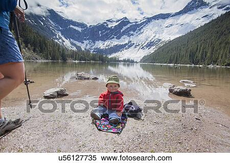 Stock Photography - Boy (4-5) sitting on lakeshore. Fotosearch