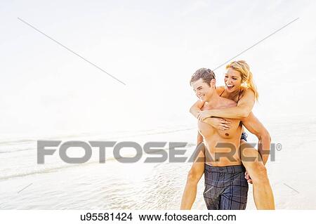 Boyfriend carrying girlfriend piggyback on beach View Large Photo Image Picture - Boyfriend carrying girlfriend piggyback on beach. Fotosearch