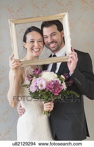 Bride and groom posing with picture frame View Large Photo Image Picture - Bride and groom posing with picture frame . Fotosearch