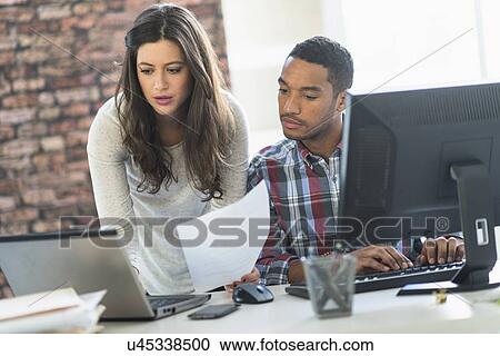 Stock Image - Business couple working in office. Fotosearch