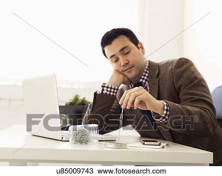 Businessman sitting in office and playing with paper clips View Large Photo Image Stock Image - Businessman sitting in office and playing with paper clips. Fotosearch