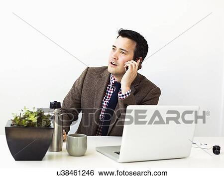 Businessman sitting in office and making phone call View Large Photo Image Stock Photograph - Businessman sitting in office and making phone call. Fotosearch