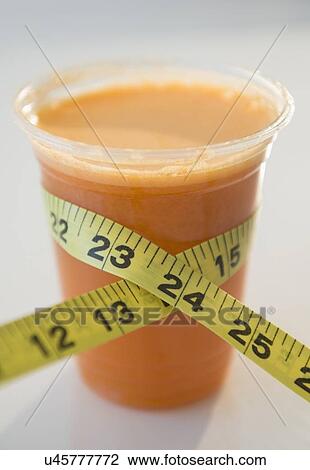 Stock Image - Carrot juice and tape measure. Fotosearch