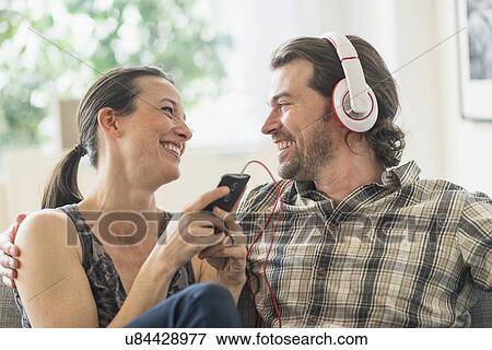 Stock Photo - Cheerful couple listening to music at home. Fotosearch