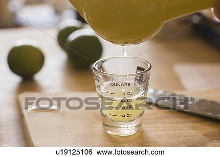 Stock Photograph - Close-up of liquid being poured into shot glass. Fotosearch