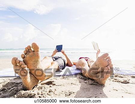 Close-up of sand-covered feet of young couple lying on blanket on beach reading View Large Photo Image Stock Image - Close-up of sand-covered feet of young couple lying on blanket on beach reading . Fotosearch