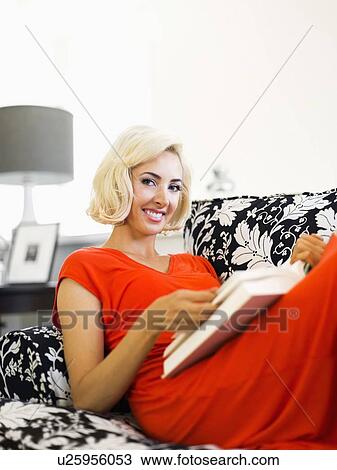 Close-up of woman lying down on sofa and holding book View Large Photo Image Stock Image - Close-up of woman lying down on sofa and holding book. Fotosearch