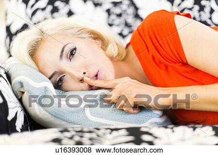 Close-up of woman lying down on sofa and keeping finger on lips View Large Photo Image Stock Photo - Close-up of woman lying down on sofa and keeping finger on lips. Fotosearch