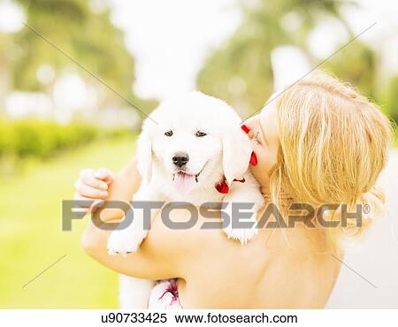 Stock Photography - Close-up shot of young woman embracing white puppy. Fotosearch
