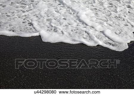 Stock Image - Close-up view of sandy beach and wave. Fotosearch