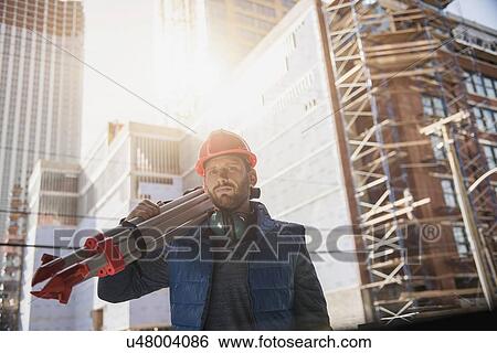 Construction worker carrying tripod on shoulder View Large Photo Image Stock Photograph - Construction worker carrying tripod on shoulder. Fotosearch